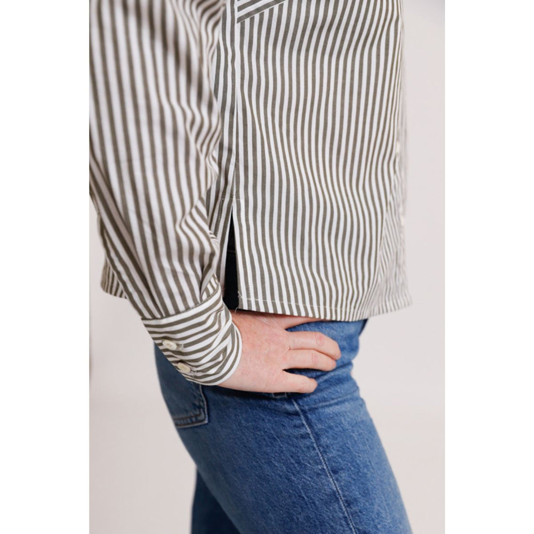 Person wearing a striped shirt and blue jeans on a plain background