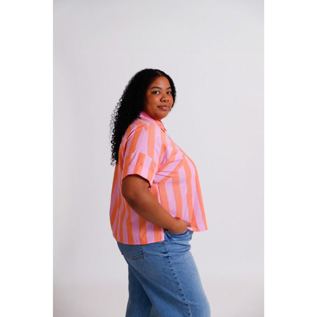 Woman wearing a pink and orange striped shirt with blue jeans on a white background