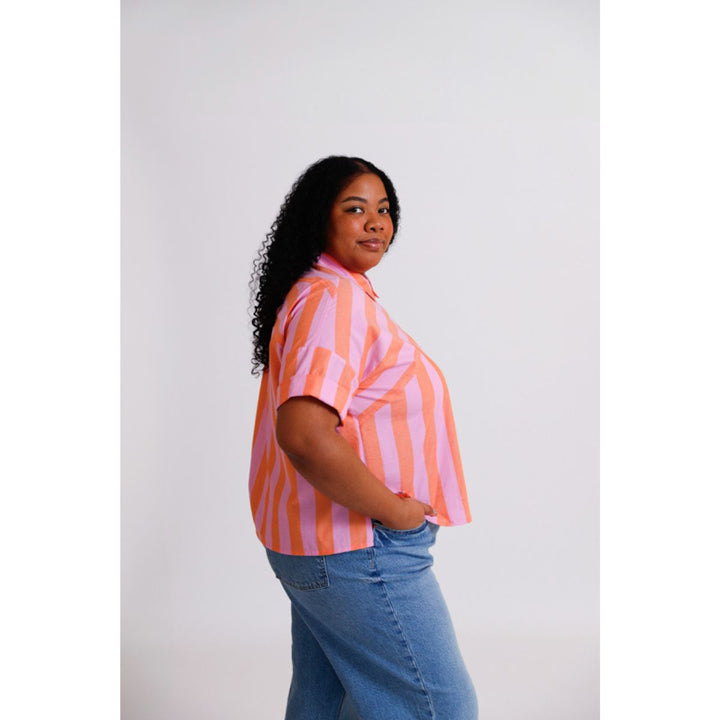 Woman wearing a pink and orange striped shirt with blue jeans on a white background