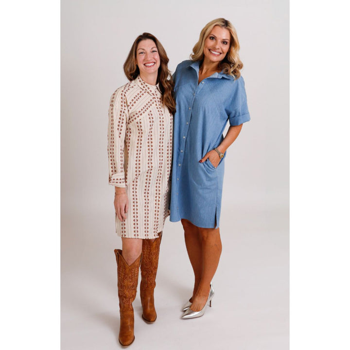 Two women wearing button-up dresses standing side by side on a white background