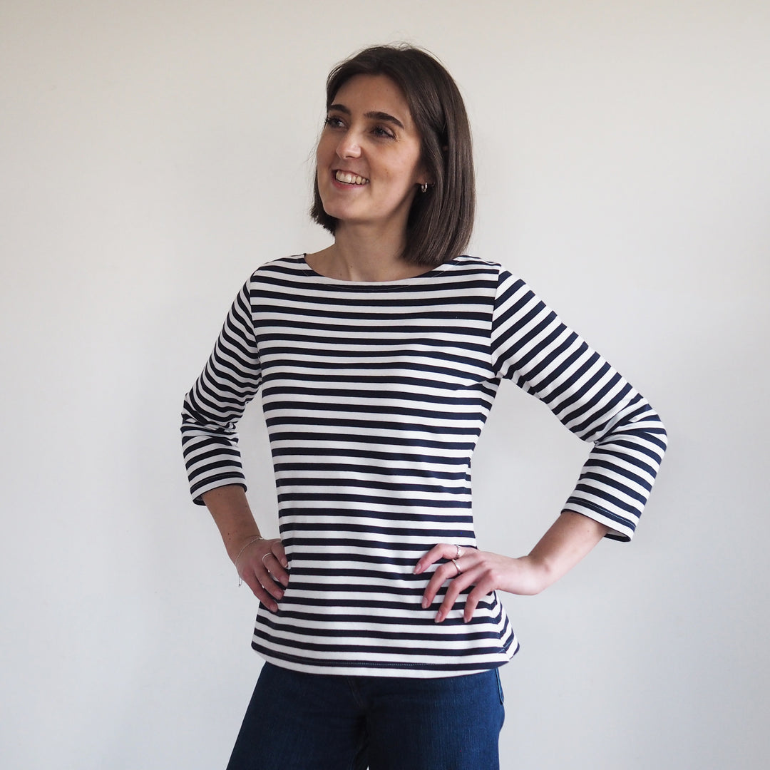 a lady with hands on hip, wearing a navy striped breton style top, made from yarn dyed loopback french terry.