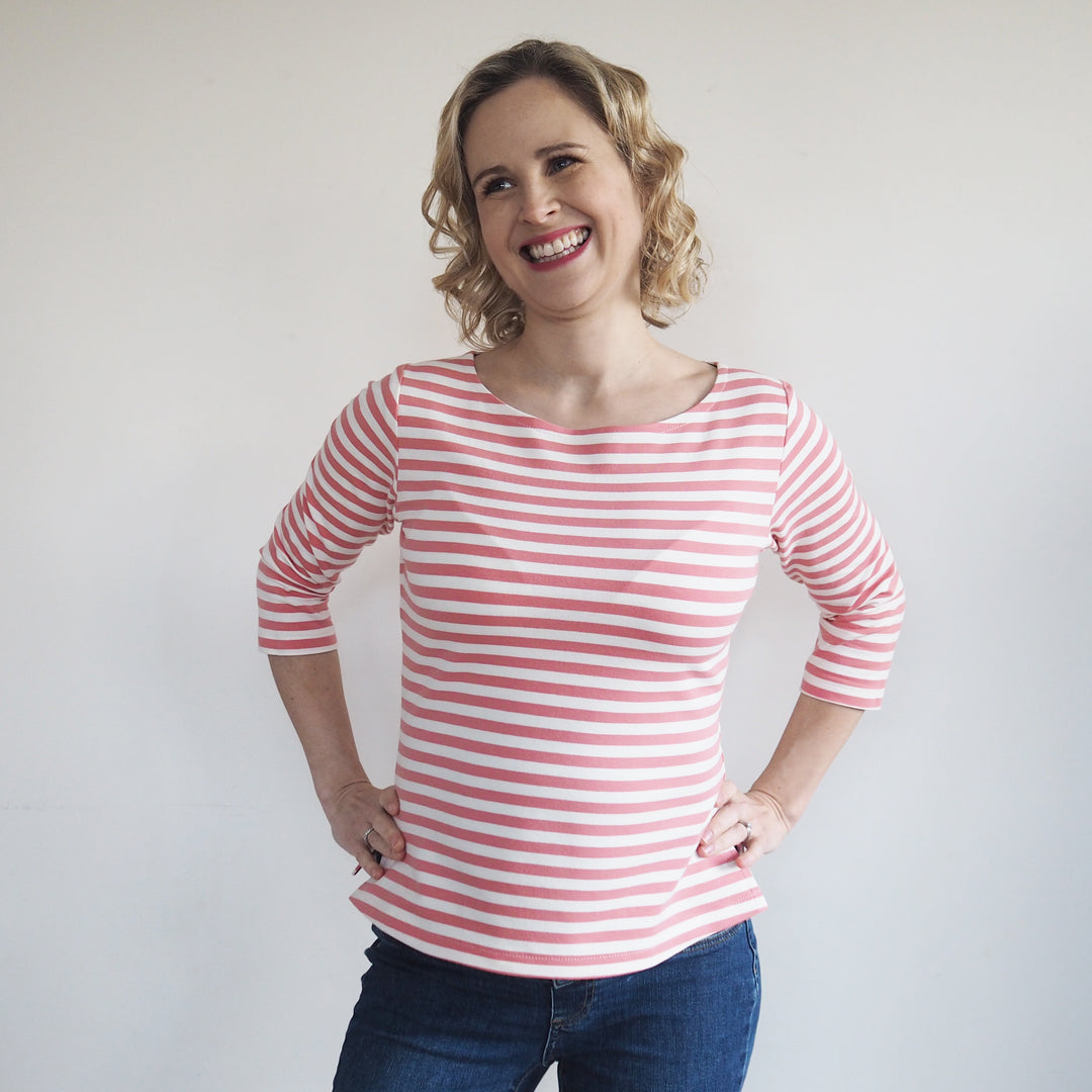 a lady with hands on hip, wearing a pink striped breton style top, made from yarn dyed loopback french terry.