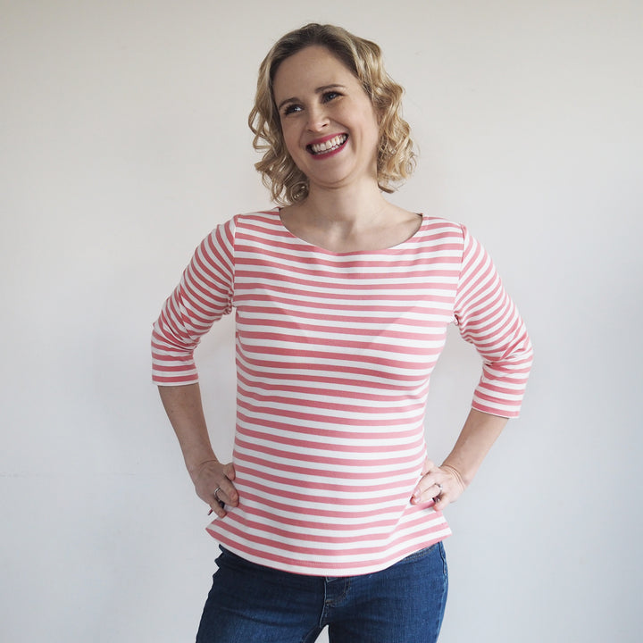 a lady with hands on hip, wearing a pink striped breton style top, made from yarn dyed loopback french terry.