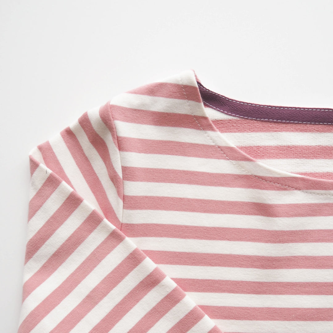 close up of a complete pink strip breton style top with a plum twill tape detail on neckline