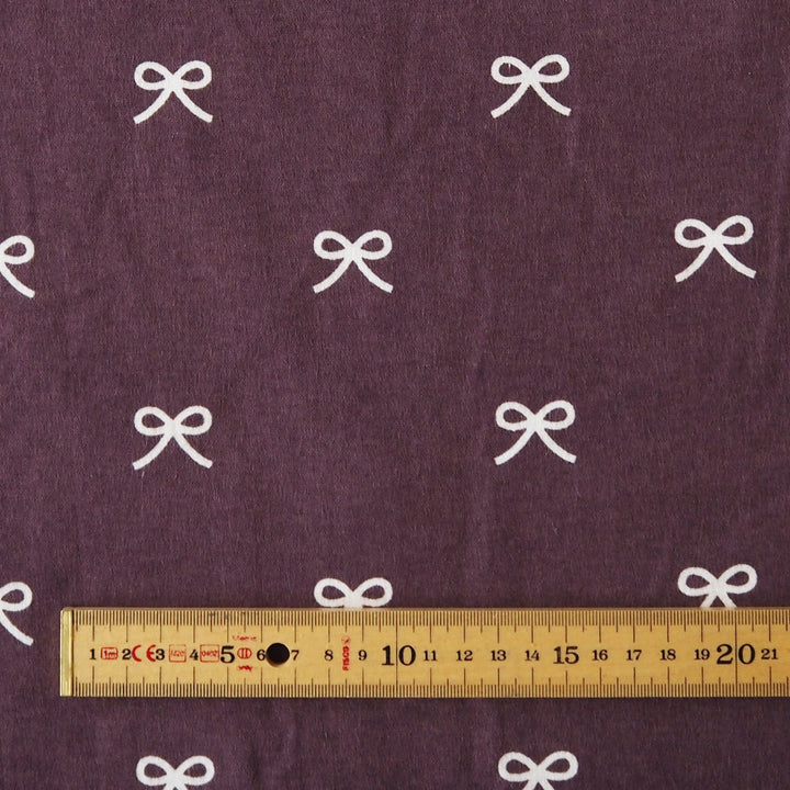 Pretty Bow Cotton Flannel Fabric with white bow print on a purple background