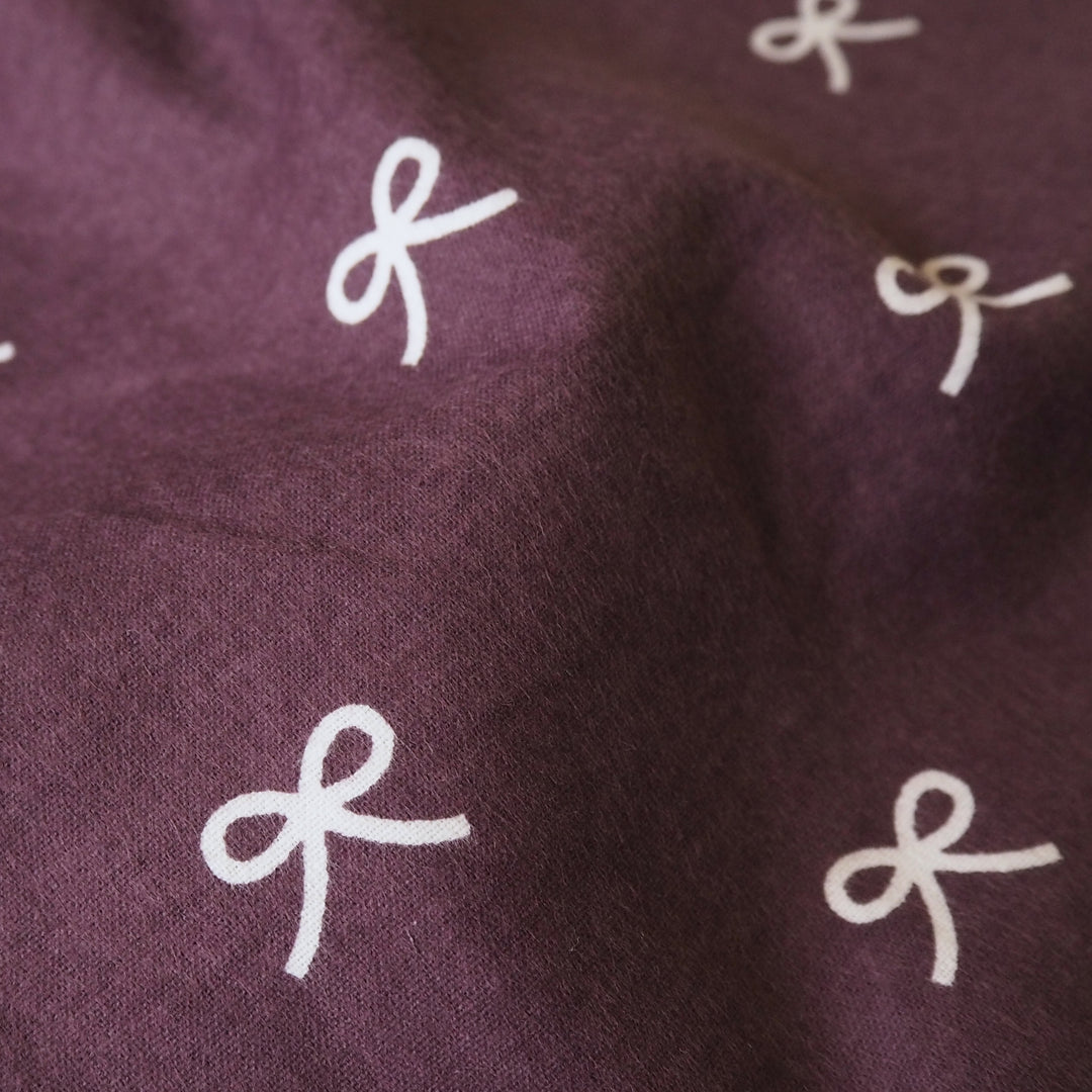 Pretty Bow Cotton Flannel Fabric with white bow print on a purple background