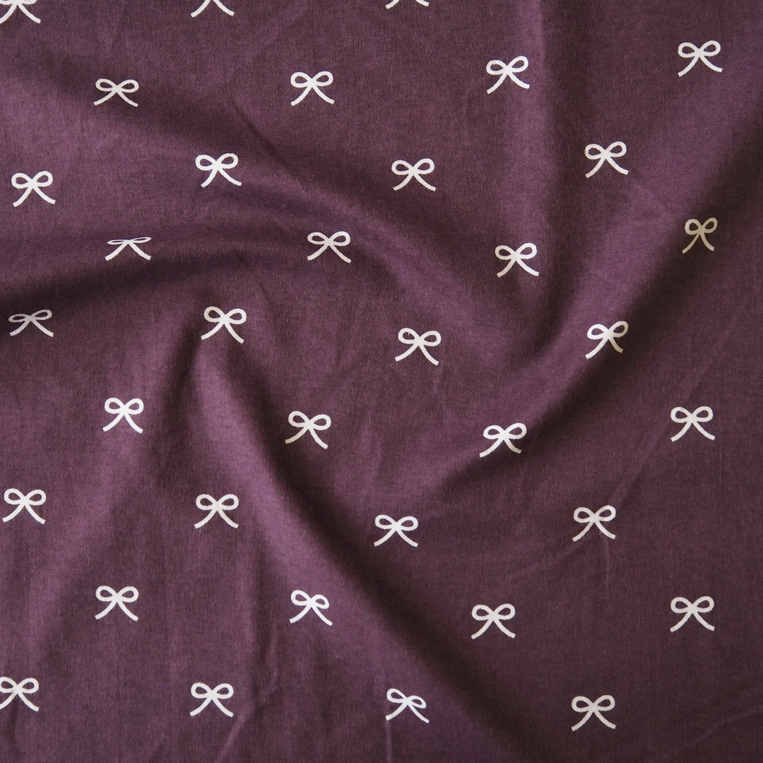 Pretty Bow Cotton Flannel Fabric with white bow print on a purple background