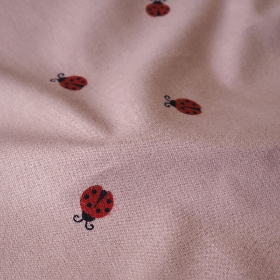 Ladybird Scatter Cotton Flannel Fabric with Red Ladybirds on a mauve pink background