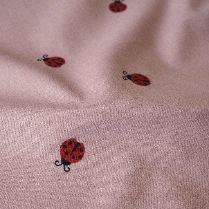 Ladybird Scatter Cotton Flannel Fabric with Red Ladybirds on a mauve pink background