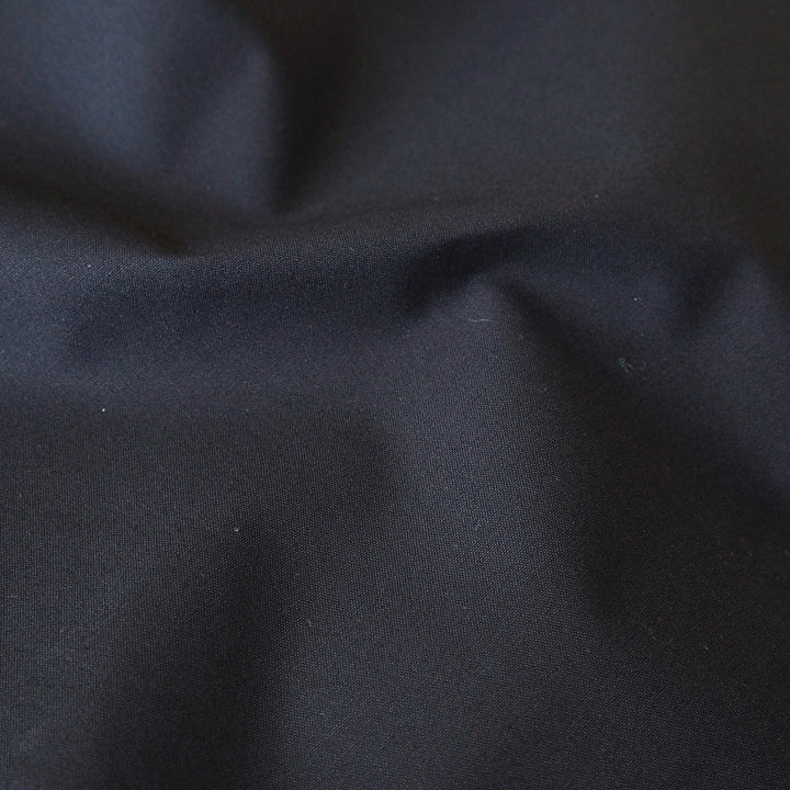 Navy waxed cotton fabric with water-resistant finish for outerwear sewing.