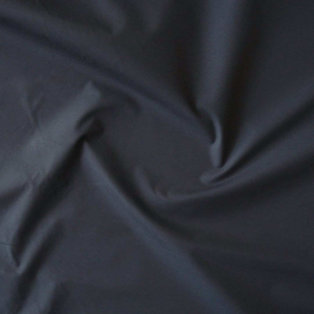 Navy waxed cotton fabric with water-resistant finish for outerwear sewing.