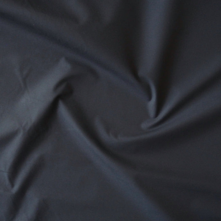 Navy waxed cotton fabric with water-resistant finish for outerwear sewing.