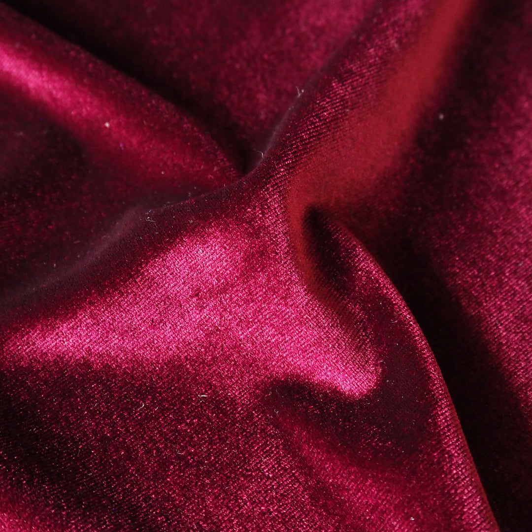 Wine red stretch velour fabric with soft sheen for dressmaking.