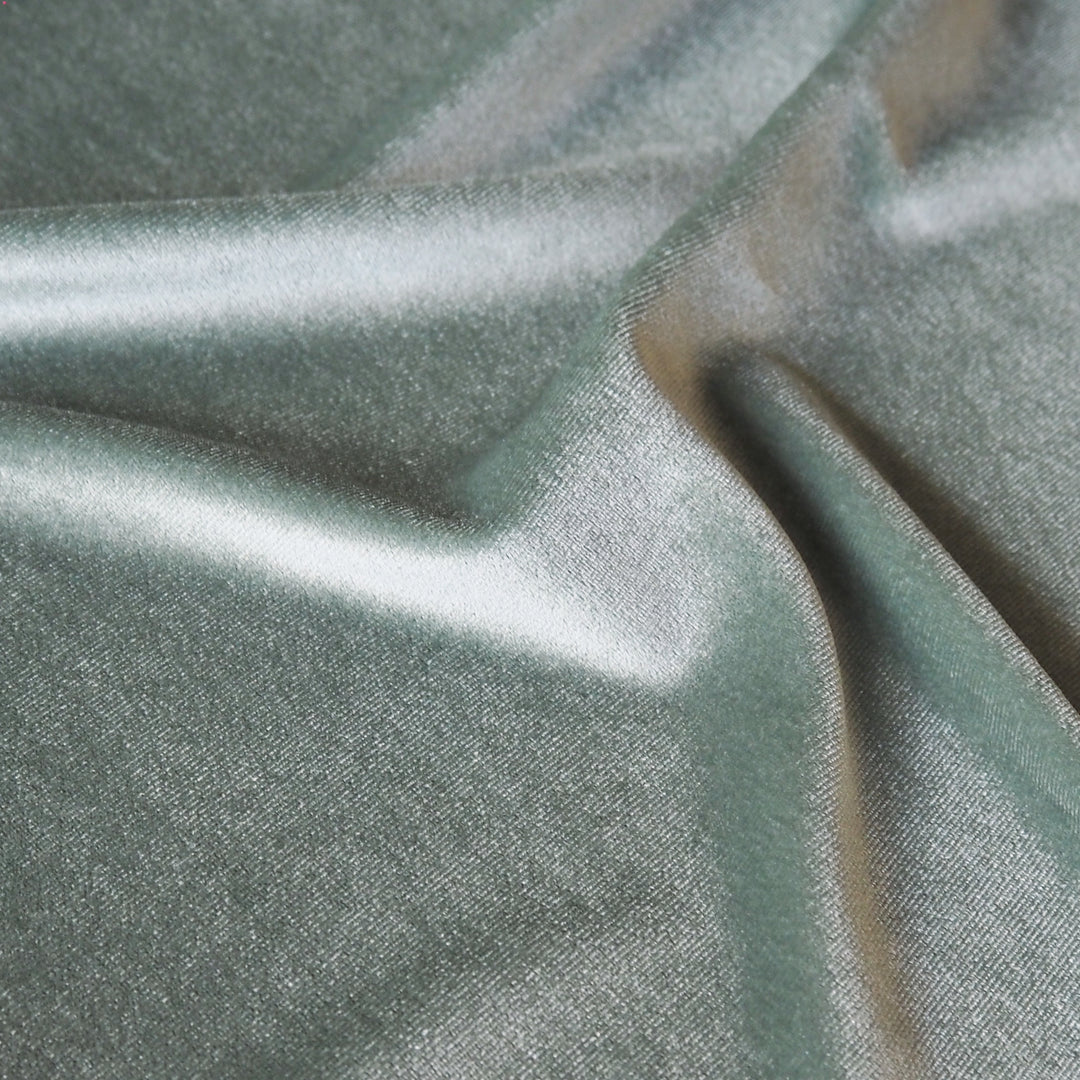 Soft sage green stretch velour fabric with soft sheen for dressmaking.