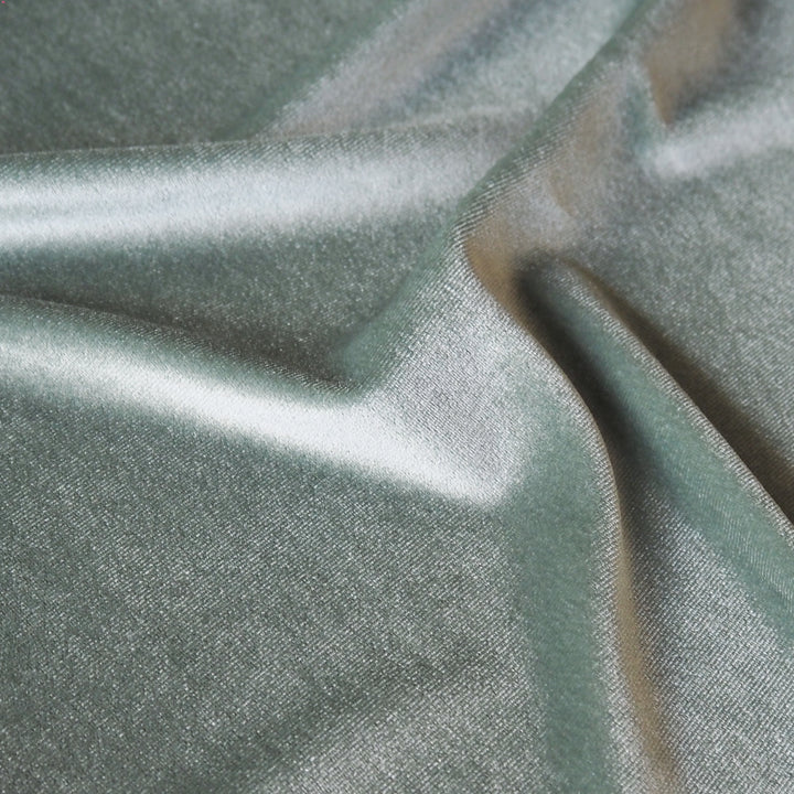 Soft sage green stretch velour fabric with soft sheen for dressmaking.