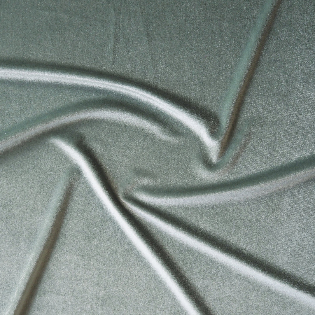 Soft sage green stretch velour fabric with soft sheen for dressmaking.