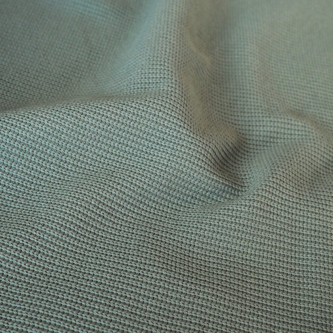 Close-up of sage green ribbed knitted fabric with visible texture