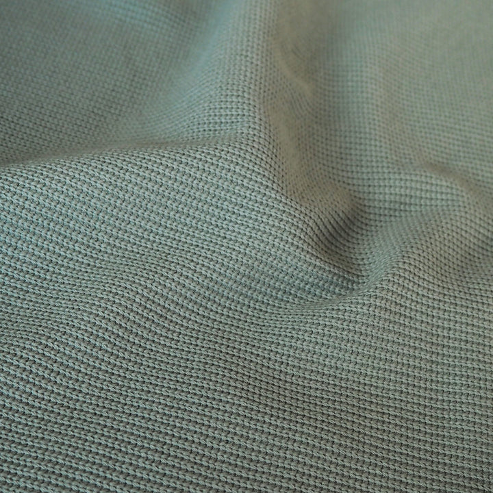 Close-up of sage green ribbed knitted fabric with visible texture