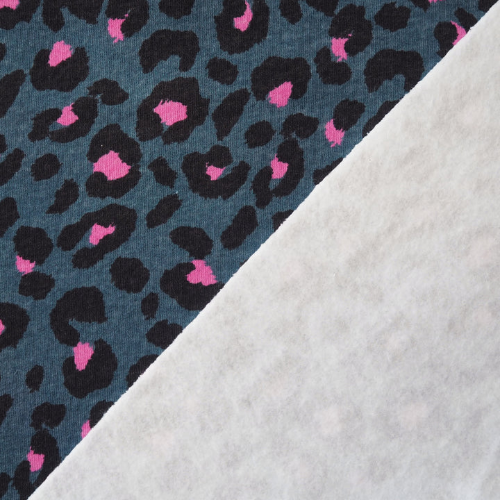 Leopard print fleeceback sweatshirt fabric with black and pink spots on an indigo blue background