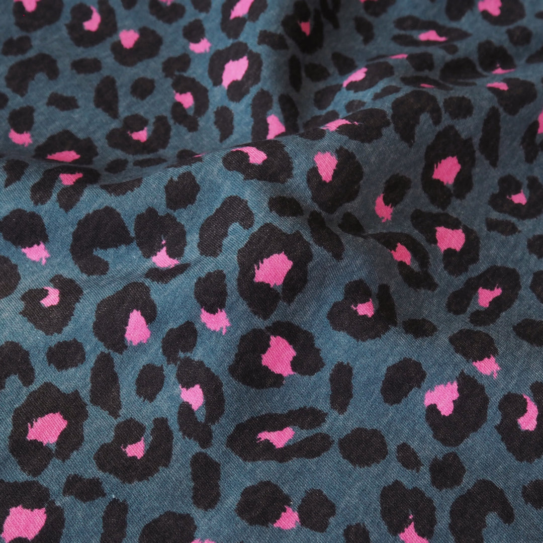 Leopard print fleeceback sweatshirt fabric with black and pink spots on an indigo blue background
