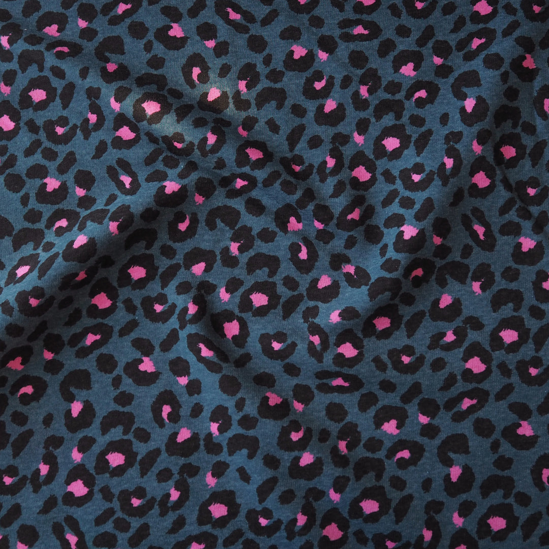 Leopard print fleeceback sweatshirt fabric with black and pink spots on an indigo blue background