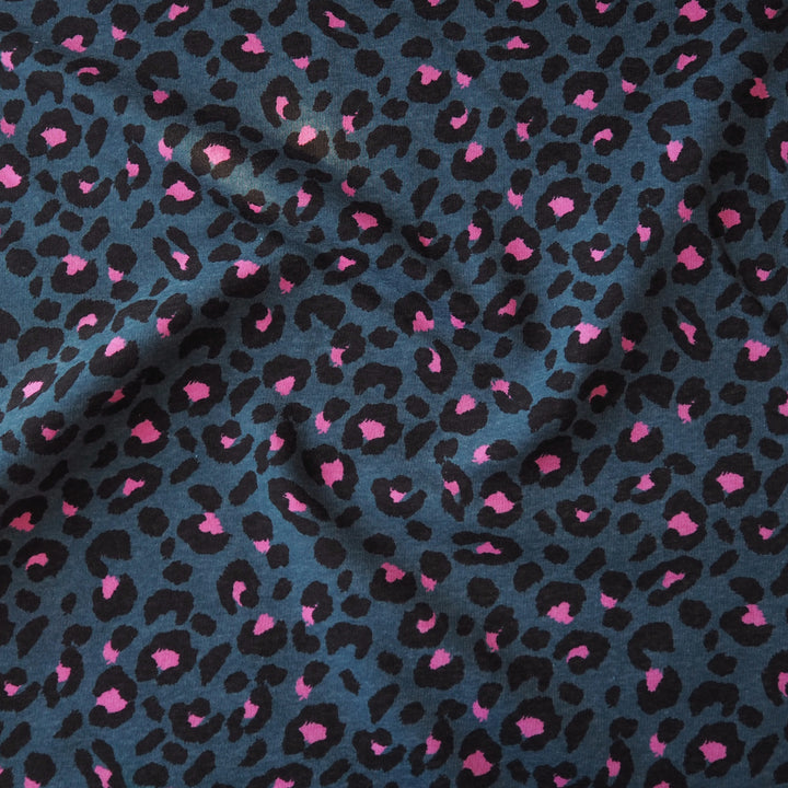 Leopard print fleeceback sweatshirt fabric with black and pink spots on an indigo blue background