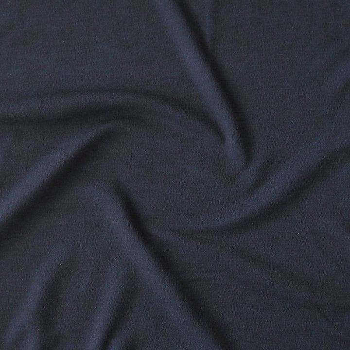 Close-up of navy blue merino wool jersey fabric with visible texture