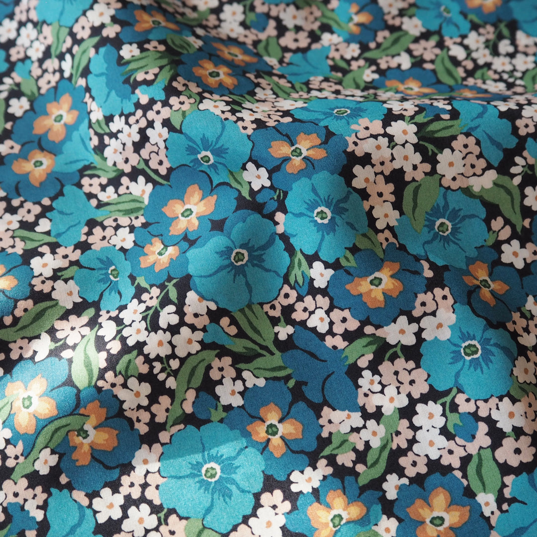 Liberty floral fabric pattern with blue, orange, and white flowers on a black background