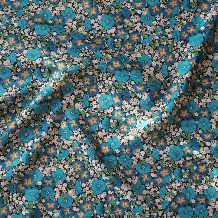 Liberty floral fabric pattern with blue, orange, and white flowers on a black background