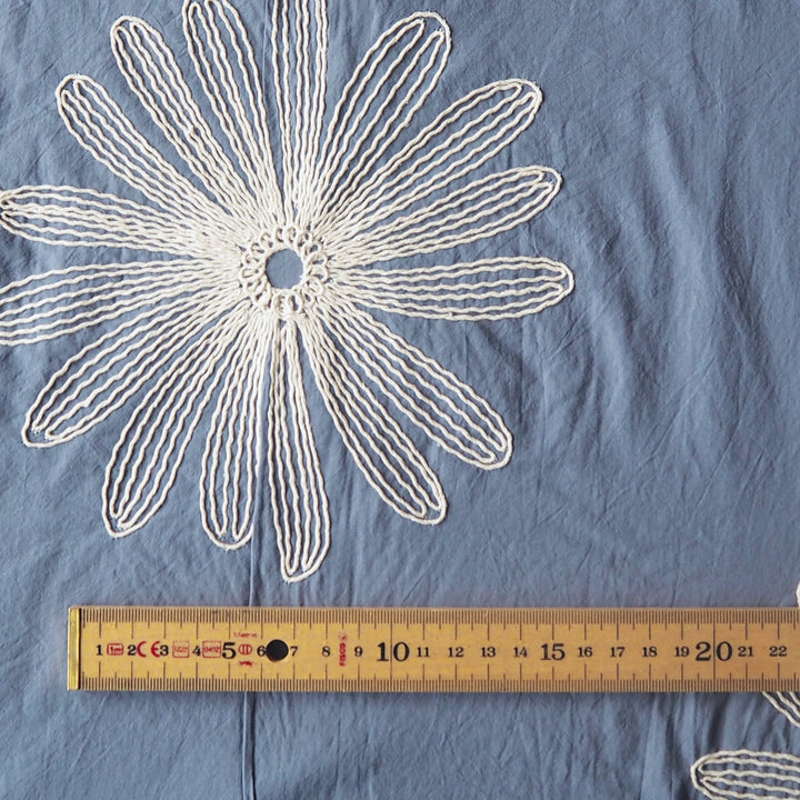 Chalky blue large scale embroidered daisy cotton dressmaking fabric