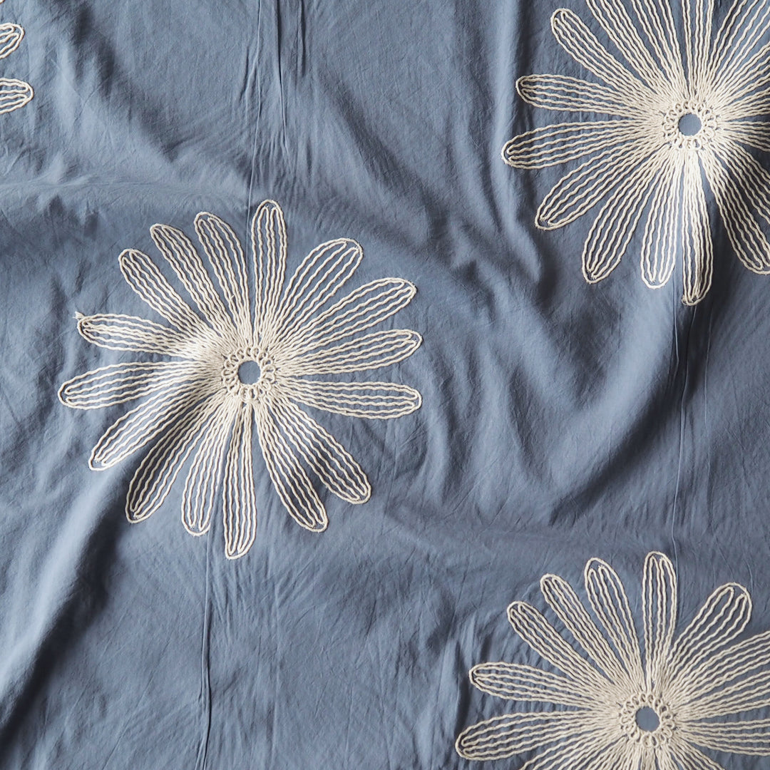 Chalky blue large scale embroidered daisy cotton dressmaking fabric