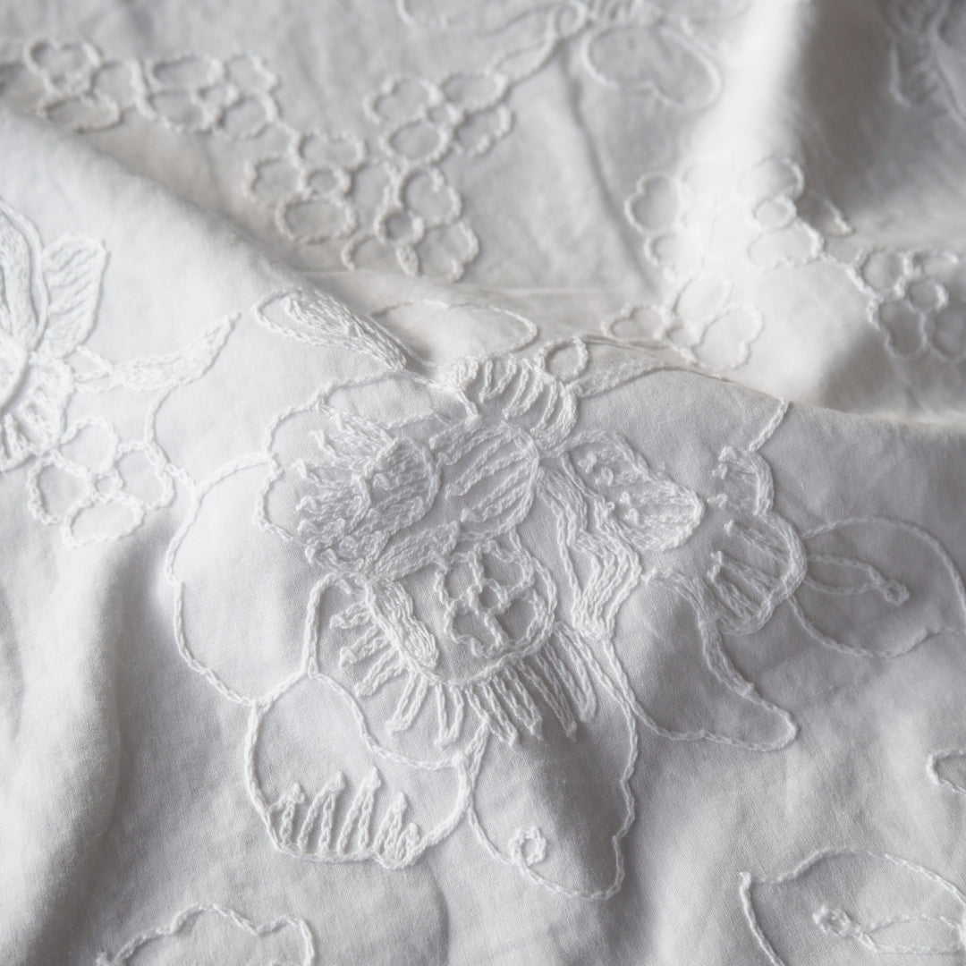 White cotton voile dressmaking fabric with embroidered floral design
