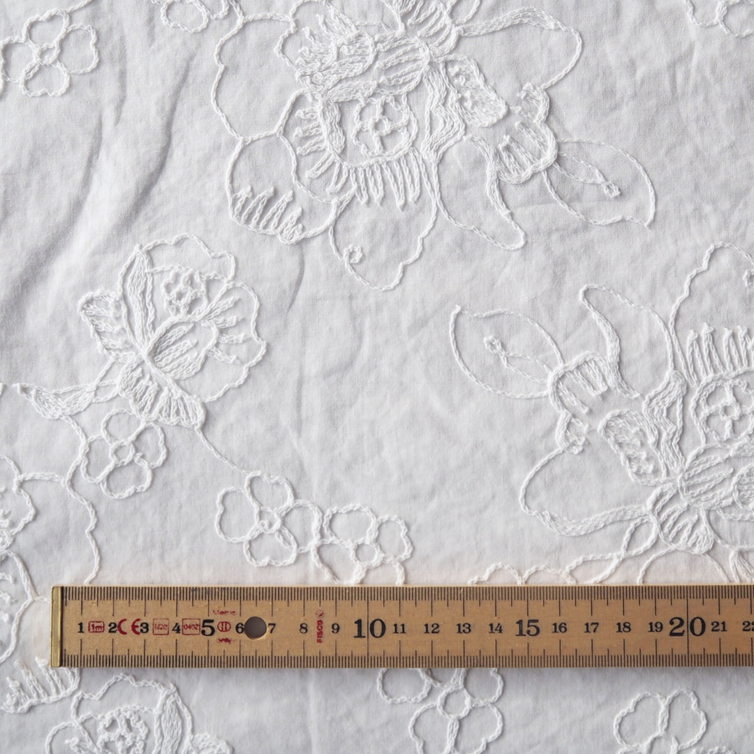 White cotton voile dressmaking fabric with embroidered floral design