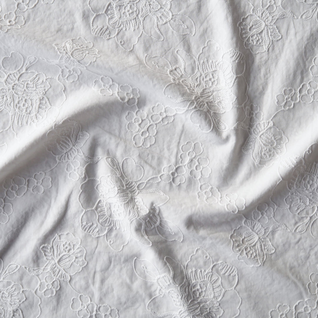 White cotton voile dressmaking fabric with embroidered floral design