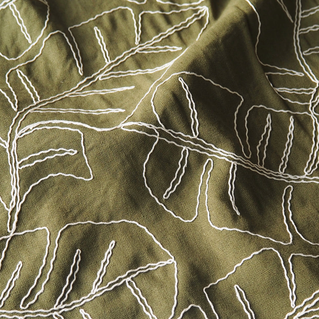 Olive green viscose linen dressmaking fabric with embroidered banana leaf pattern