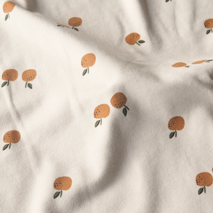 Ecru stretch cotton jersey dressmaking fabric with orange motifs