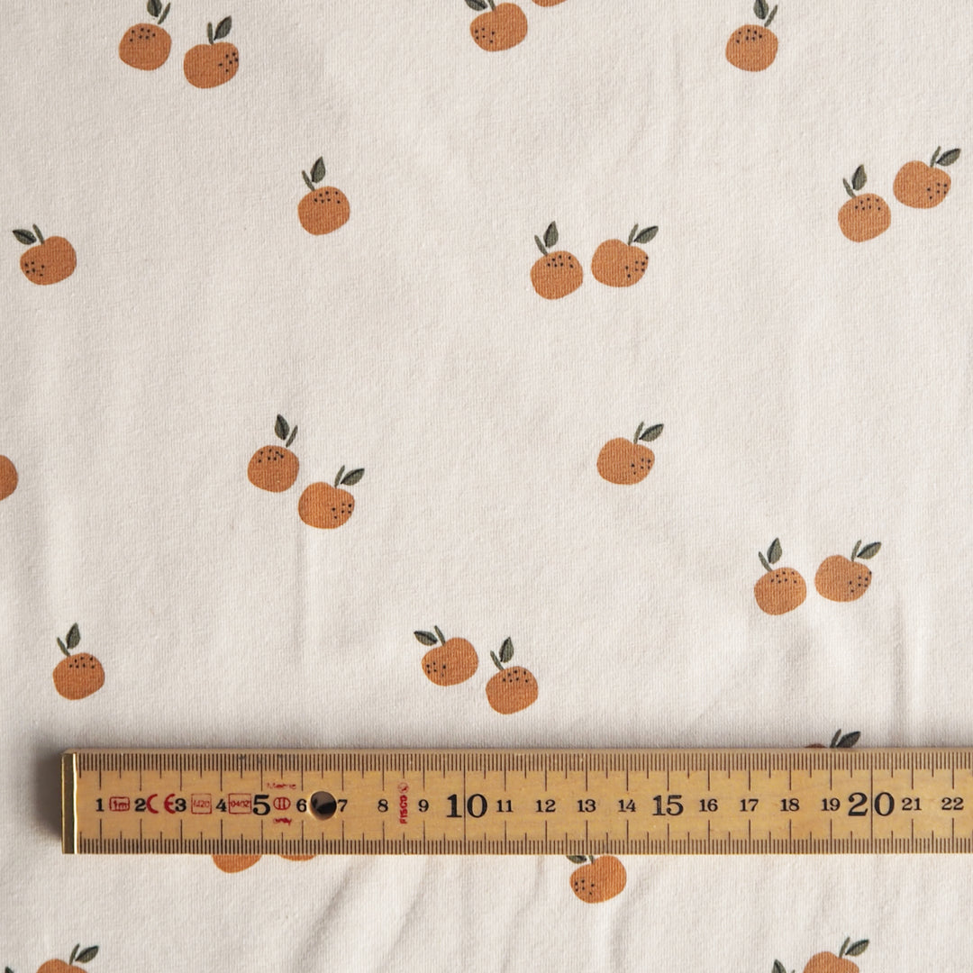 Ecru stretch cotton jersey dressmaking fabric with orange motifs