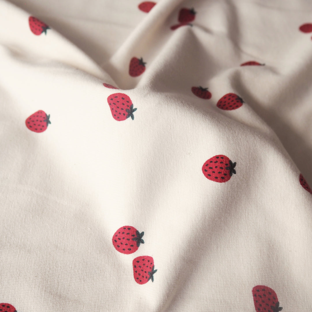 Ecru stretch cotton jersey dressmaking fabric with strawberry motifs