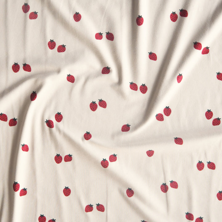 Ecru stretch cotton jersey dressmaking fabric with strawberry motifs