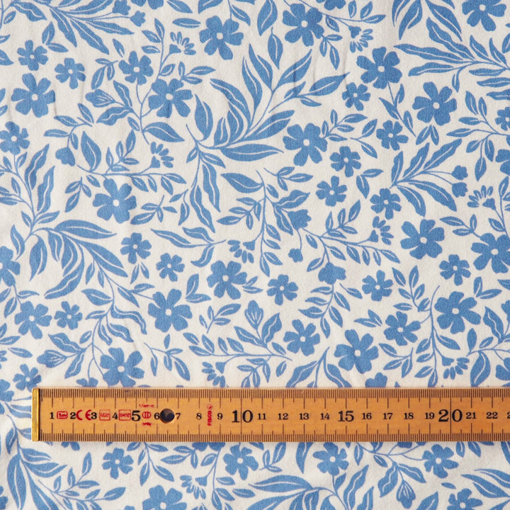 Stretch cotton jersey dressmaking fabric with blue floral pattern on a white background