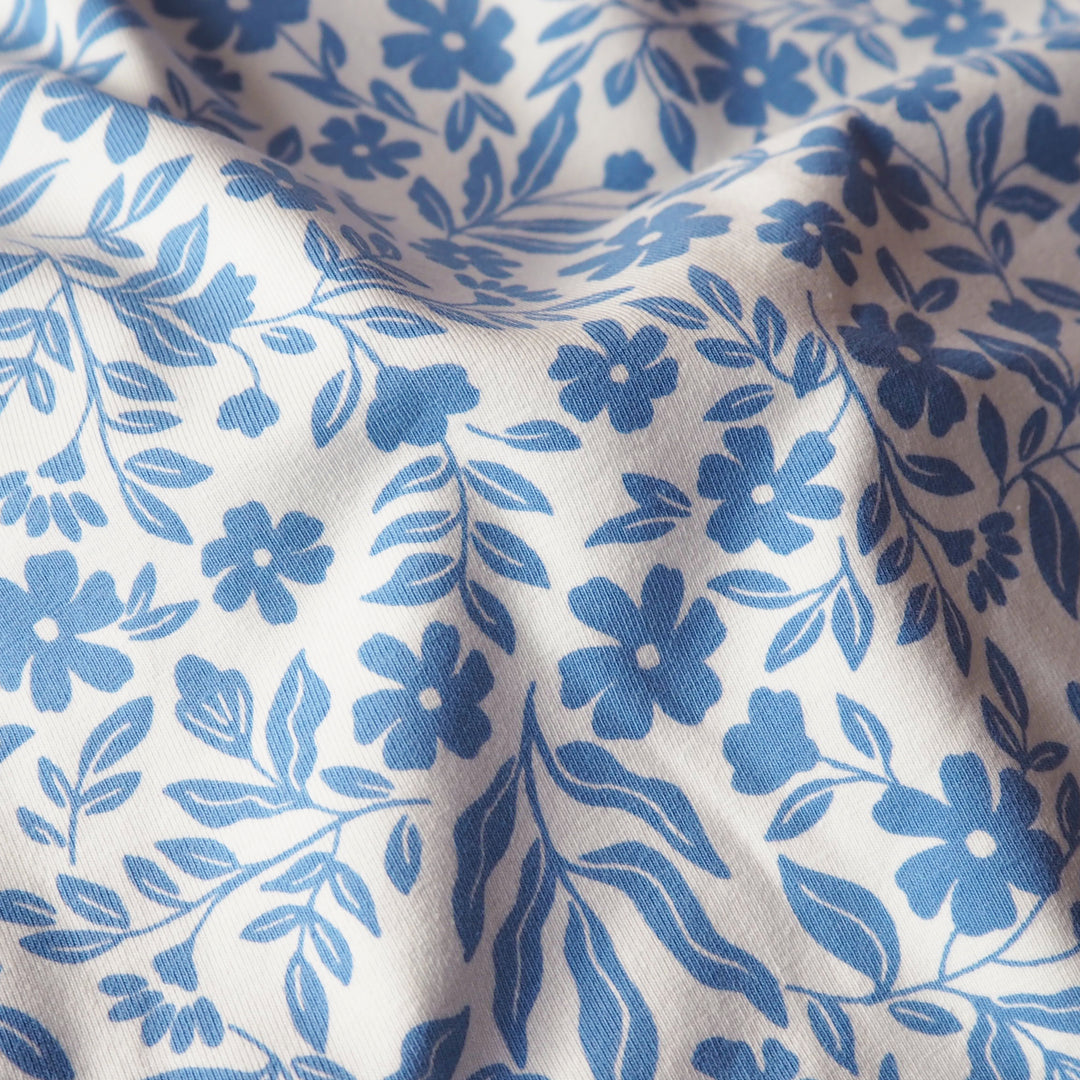 Stretch cotton jersey dressmaking fabric with blue floral pattern on a white background