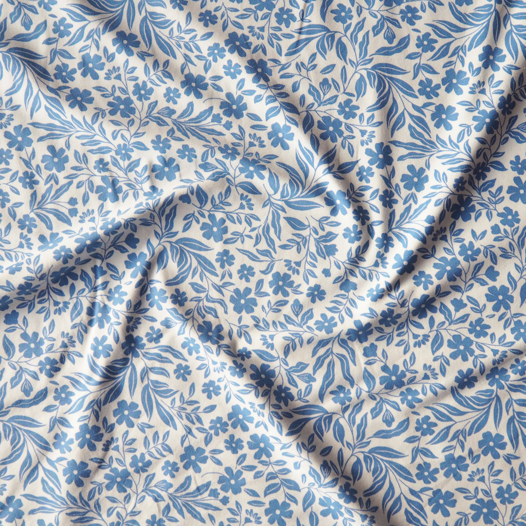 Stretch cotton jersey dressmaking fabric with blue floral pattern on a white background