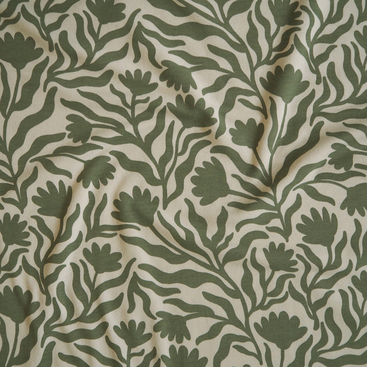 Cream sweatshirting dressmaking fabric with green floral squiggle pattern and fleeceback