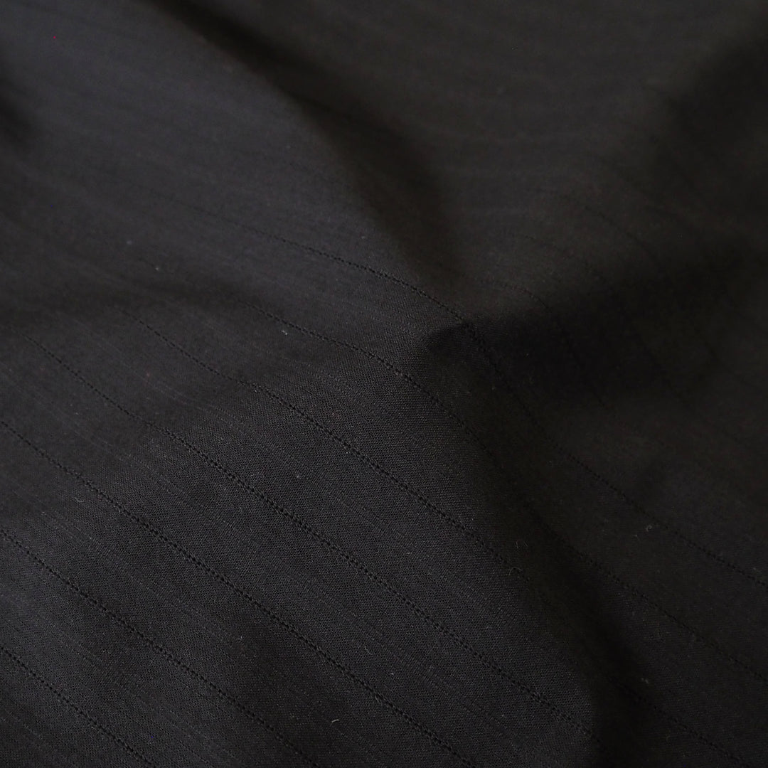 Black cotton dressmaking fabric with subtle stripe woven pattern
