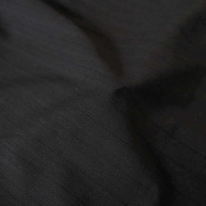 Black cotton dressmaking fabric with subtle stripe woven pattern