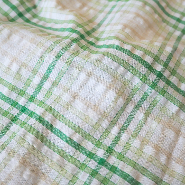 Cotton dressmaking fabric with green check on a white background