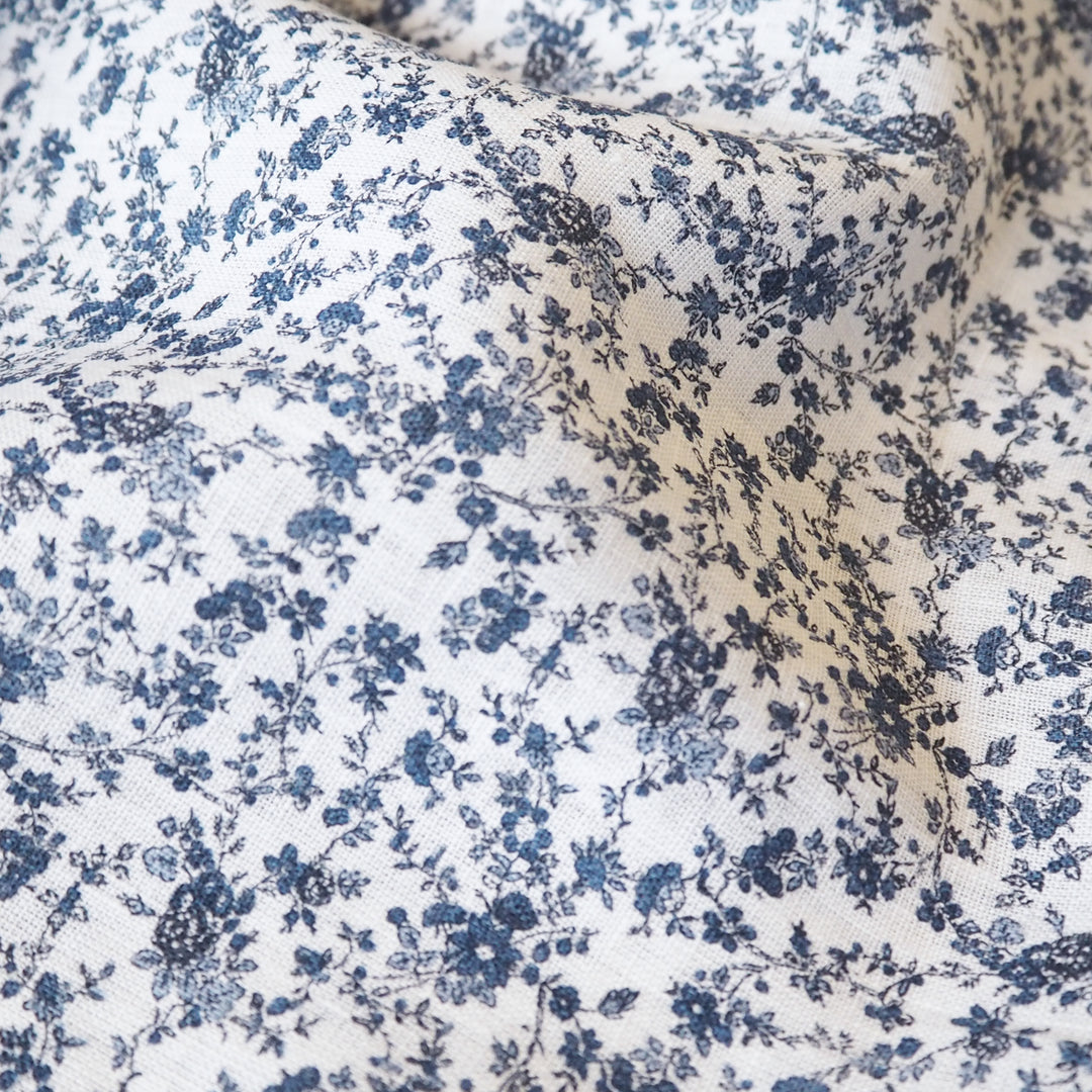White linen dressmaking fabric with blue floral pattern