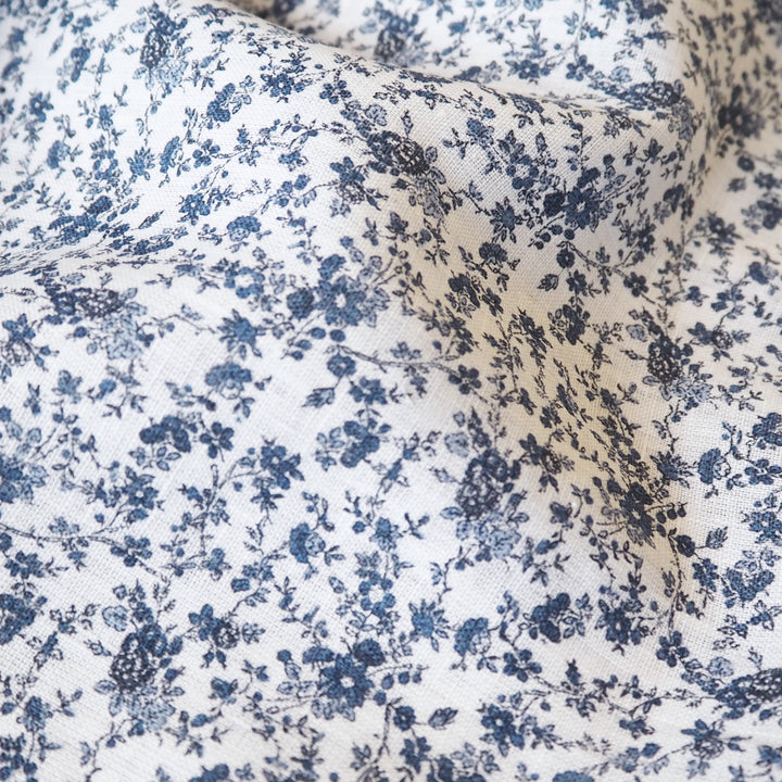 White linen dressmaking fabric with blue floral pattern