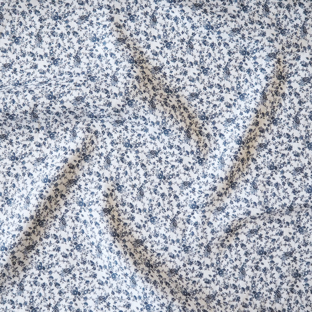 White linen dressmaking fabric with blue floral pattern