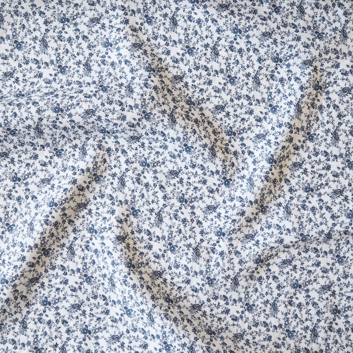 White linen dressmaking fabric with blue floral pattern